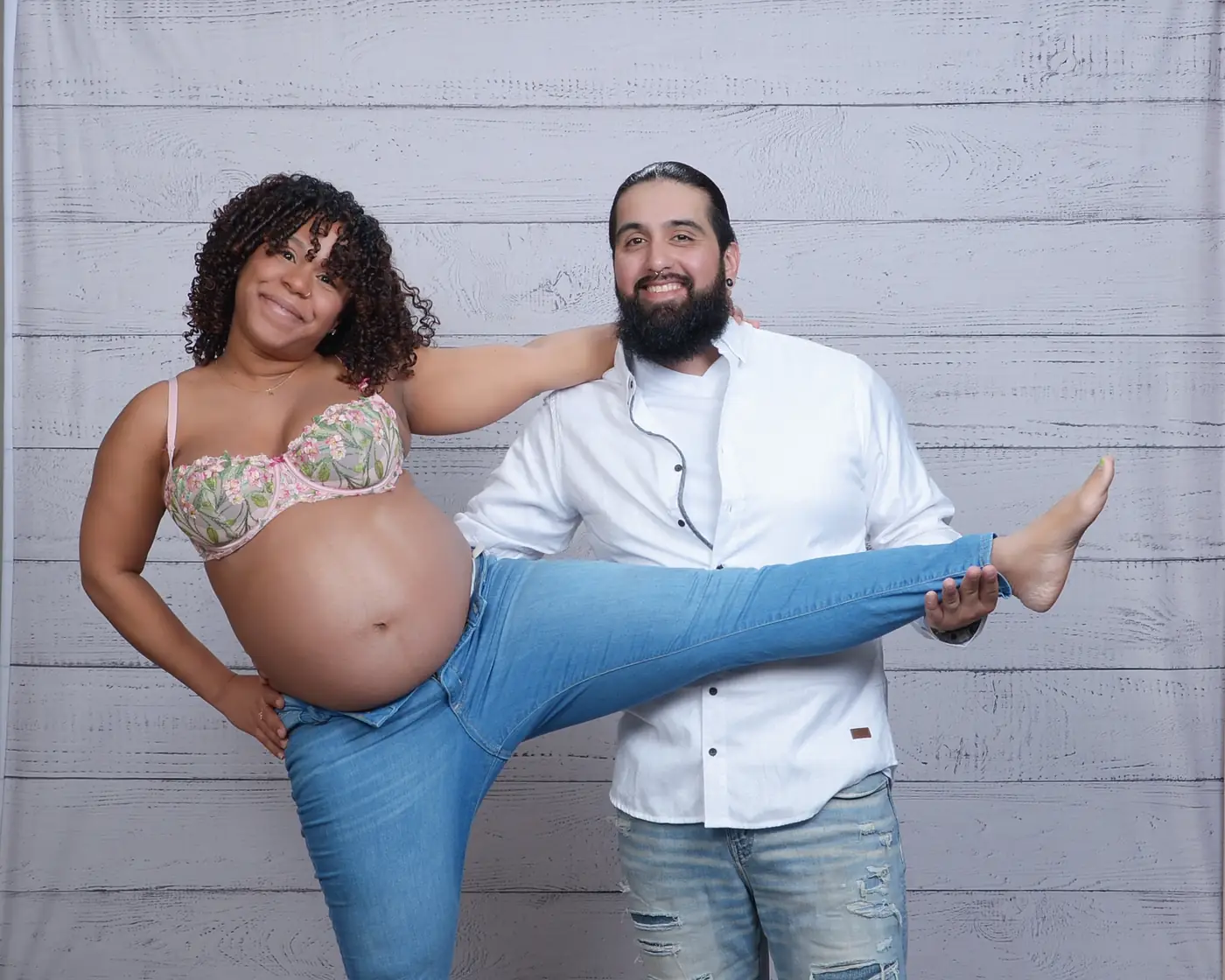Una pareja posando y riendo; ella está embarazada