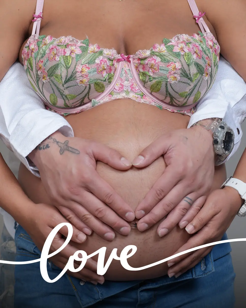 Las manos de la pareja forman un corazón sobre la barriga de embarazo