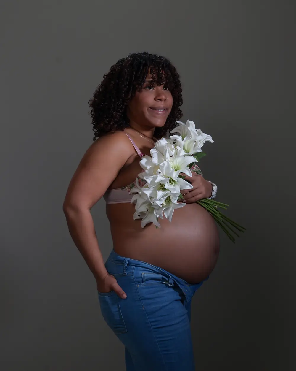 Una mamá embarazada sostiene un ramo de lirios blancos